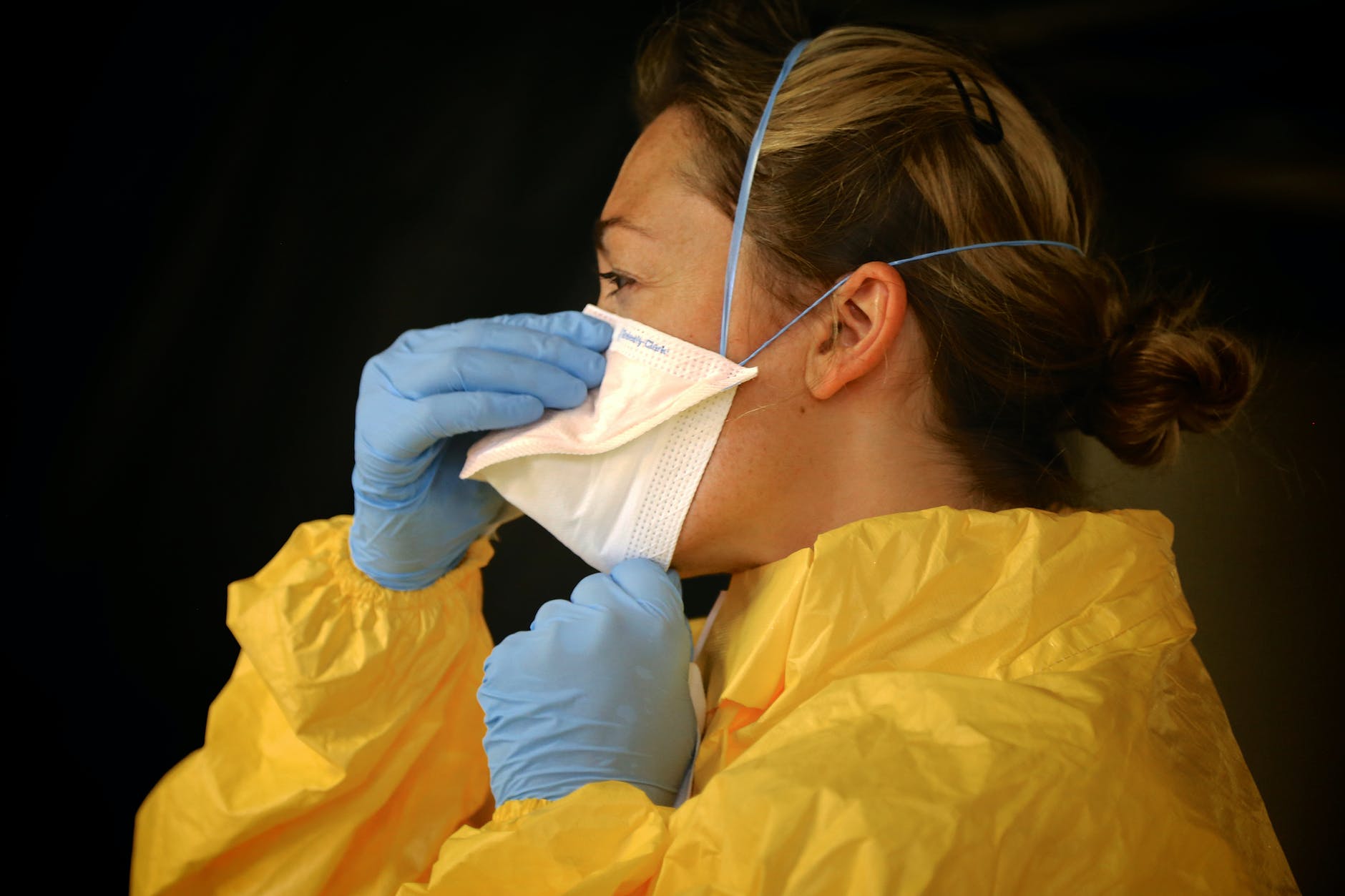 woman in yellow protective suit wearing white face mask